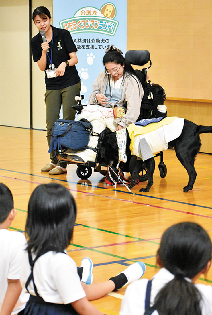 松山さん（上部右）の指示で落としたものを拾う介助犬のサスケの写真