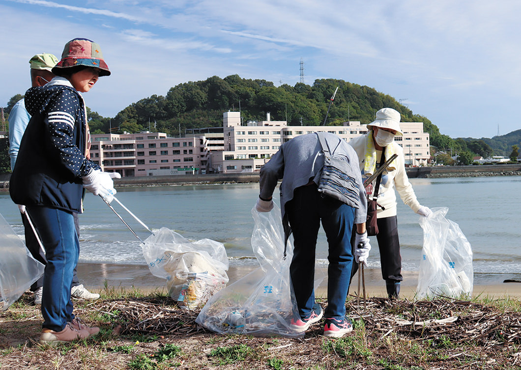 海岸に流れついたゴミを拾う女性部員の写真